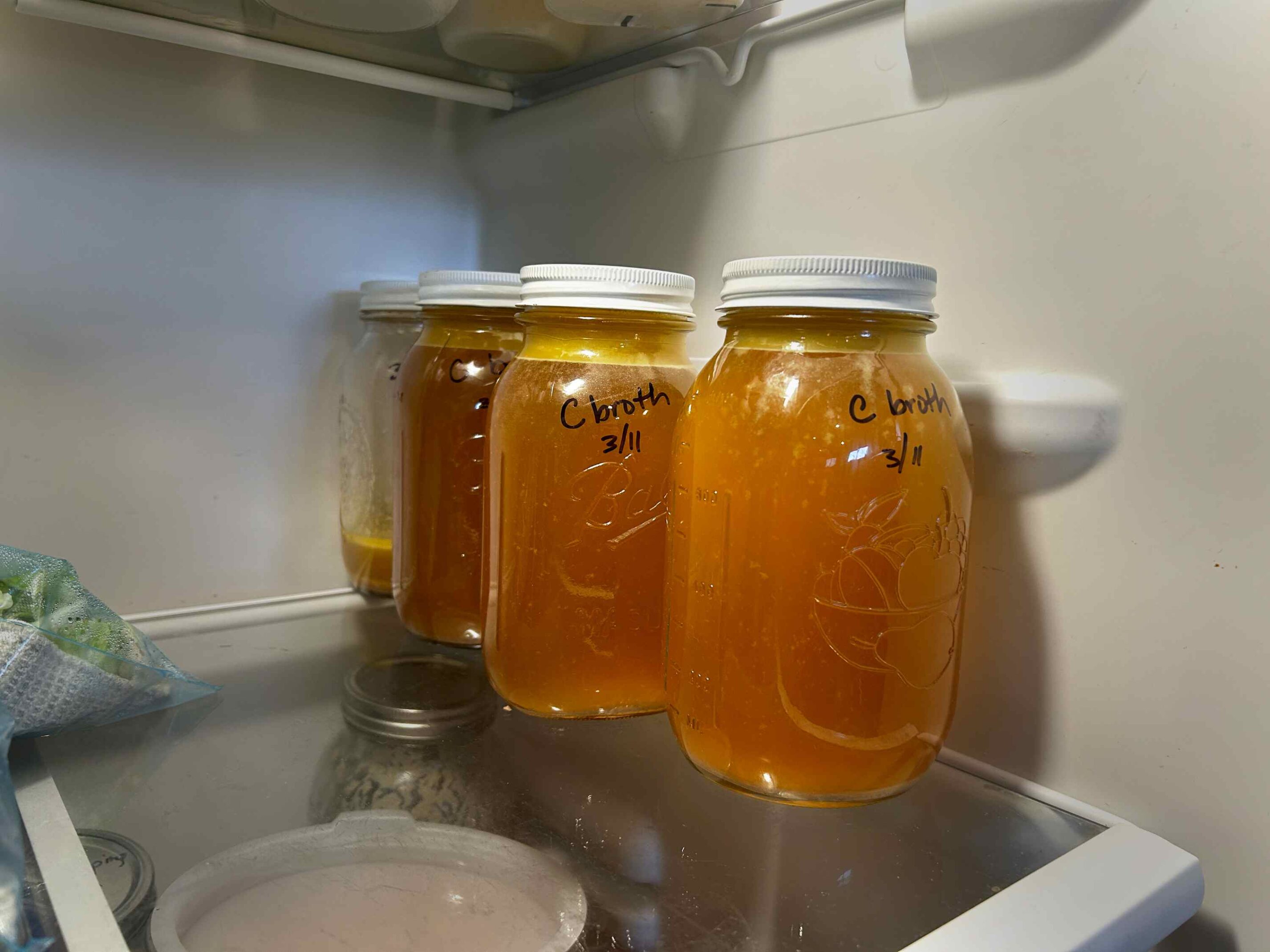 Chicken broth in quart jars sitting in the fridge